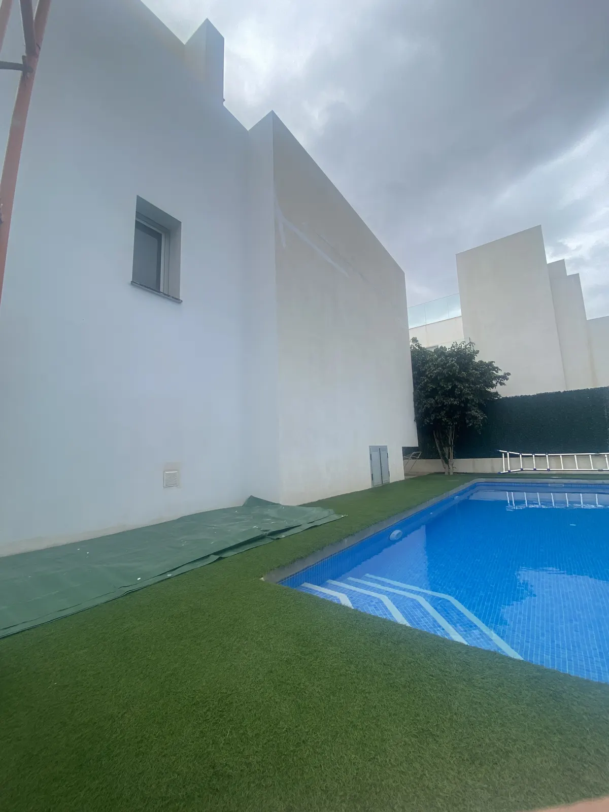 Après : façade de villa repeinte en blanc au-dessus de la piscine
