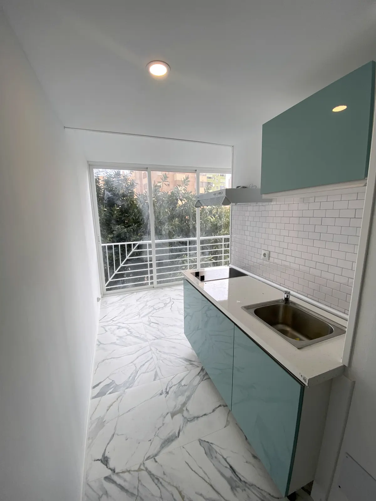 Kitchenette sur mesure et sol effet marbre dans un studio rénové